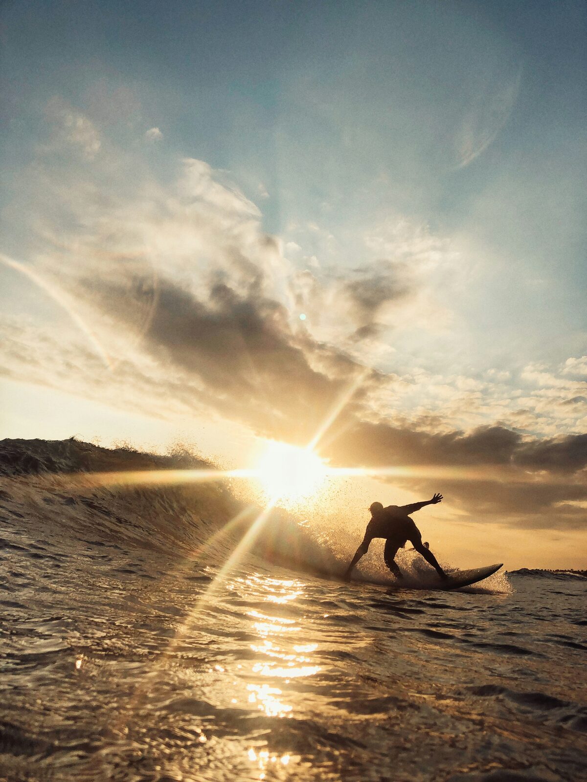 A surfer riding a wave at sunset